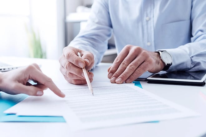 man using pen to point to contract