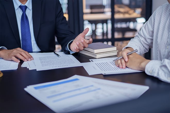 Close up of two people sitting at a table reviewing contract paperwork.