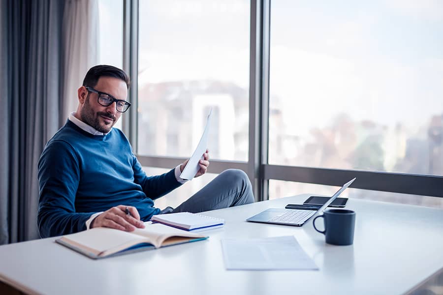 Young adult businessman sitting at a desk comparing insurance solutions.