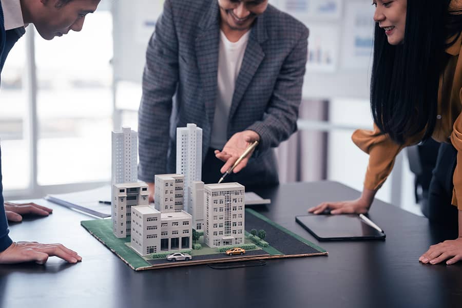 A Real Estate team looking at a 3d architectural model in a conference room.