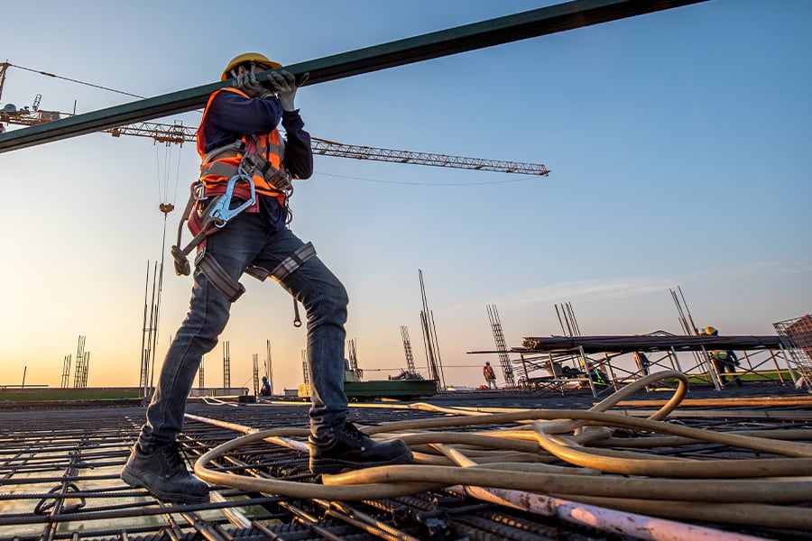 A construction worker carrying materials over their shoulder at a construction site.