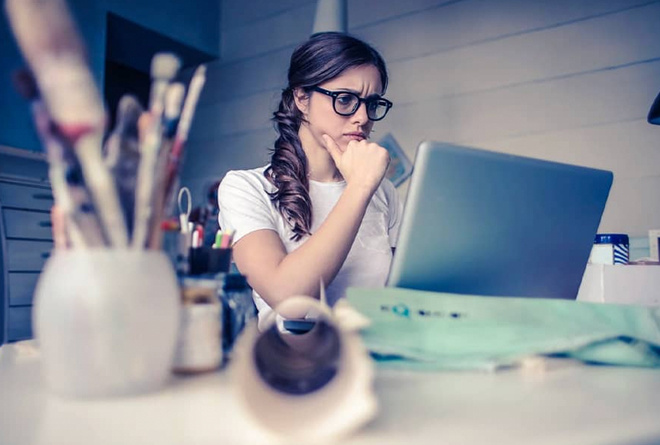 Woman frowning while looking at a laptop on her desk.